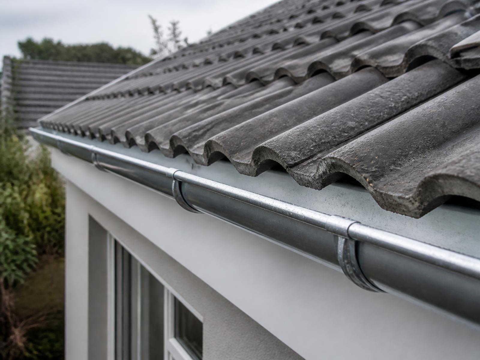 Nahaufnahme gereinigter Dachziegel mit sauberer Regenrinne am Dachrand